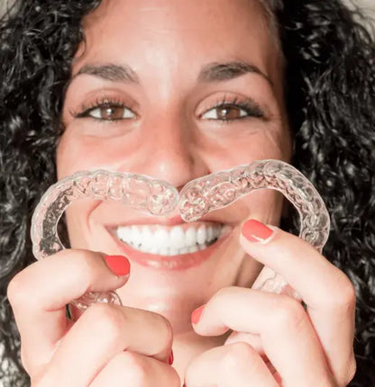 Woman holding two clear dental nightguards in front of her mouth from NightShield Dental